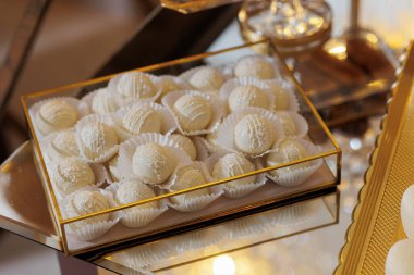 Altın kenarlı bir tepsi beyaz kurabiye. Kurabiyeler temiz bir kabın içinde ve pudra şekeriyle kaplı.