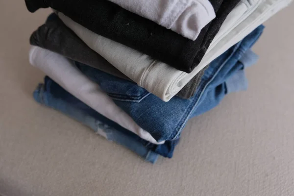 Denim fabric, folded and stacked denim pants on a white sofa, denim fabric concept idea photo.