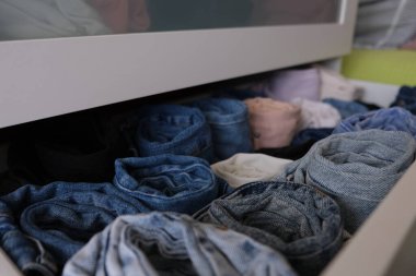 Bir sandık dolusu kot pantolon, neredeyse açık çekmece ve kapalı alanda kot pantolon, yakın çekim. Seçici odaklanma. Denim konsepti fotoğraf fikri.