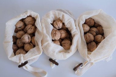 Kabuklu ceviz, kabuklu ceviz yığını, beyaz bir arka planda üç beyaz kumaş torba içinde yan yana. Kabuklu ceviz dolu kumaş torbaları konsept fotoğraf fikri.  