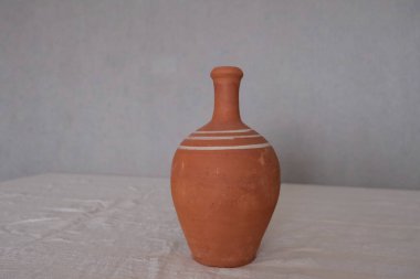 Beyaz bir masa örtüsü üzerinde boyanmamış eski antika seramik kil sürahisi. Şarap veya su içmek için kil sürahisi.