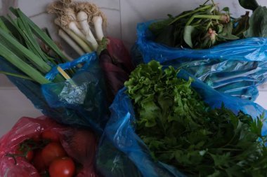 Sebze alışverişi, farklı taze sebzelerle dolu plastik poşetler mutfaktaki beyaz tezgahta..