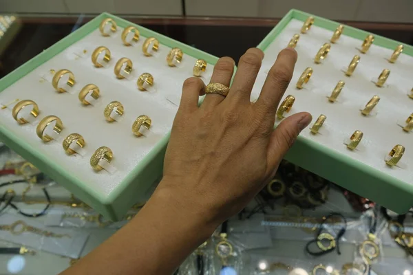 Woman hand finger trying a golden ring, golden ring on female finger at a jewelry store. Jewelry concept photo idea.