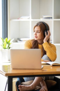 Güzel, gülümseyen, kulaklık takan, elinde kitap tutan bir öğrenci kız öğrenci portresi kafa ve el dengeleyici kitaplar taşıyor.