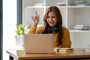 Güzel, gülümseyen, kulaklık takan, elinde kitap tutan bir öğrenci kız öğrenci portresi kafa ve el dengeleyici kitaplar taşıyor.