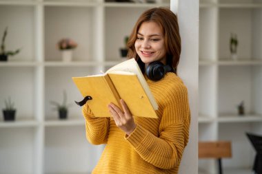 Güzel, gülümseyen, kulaklık takan, elinde kitap tutan bir öğrenci kız öğrenci portresi kafa ve el dengeleyici kitaplar taşıyor.