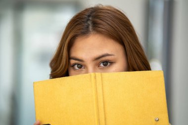 Güzel, gülümseyen, kulaklık takan, elinde kitap tutan bir öğrenci kız öğrenci portresi kafa ve el dengeleyici kitaplar taşıyor.