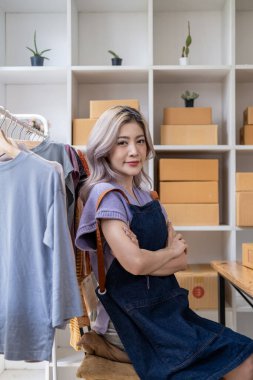 Genç, mutlu kadın moda blogcusu kadın işyeri sahibi günümüze uygun çek kıyafetlerini gösteriyor ve canlı internet dükkanında satıyor. 