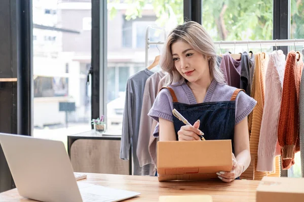 Genç, mutlu kadın moda blogcusu kadın işyeri sahibi günümüze uygun çek kıyafetlerini gösteriyor ve canlı internet dükkanında satıyor. 