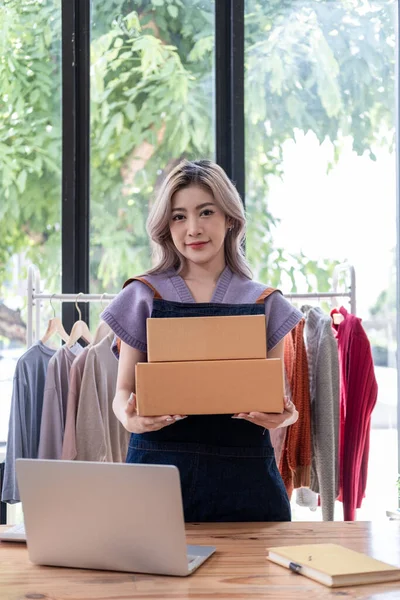 Genç, mutlu kadın moda blogcusu kadın işyeri sahibi günümüze uygun çek kıyafetlerini gösteriyor ve canlı internet dükkanında satıyor. 