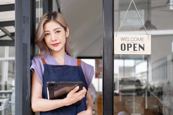 Küçük işletme sahibi, Asyalı, küçük işletme sahibi, açık tabelalı kahve dükkanı müşterileri karşılamak için restoran girişinde duran mutlu, genç işletme sahibi garson.