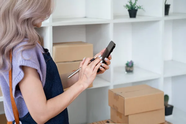 İş kadını sahibi cep telefonlu cep telefonu sahibi müşteriyle sohbet etmek için cep telefonu kullanıyor. Telefon ve perakende ürün taşıyan küçük işletme sahibi teslimat için hazırlanıyor.