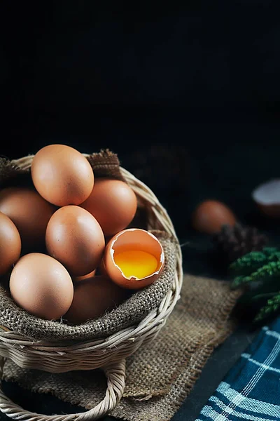 Sepetteki yumurta, koyu arkaplan ve yumurtalardan biri kırılmış.