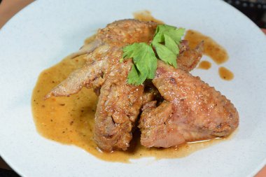 Tavuk kanadı. Beyaz tabakta servis edilen baharatlı körili tavuk.