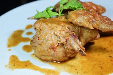 Tavuk kanadı. Beyaz tabakta servis edilen baharatlı körili tavuk.