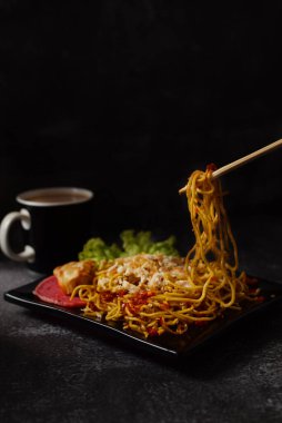 Baharatlı şehriye, acılı ve tavuklu, sebzeli ve koyu arkaplanda bir fincan kahve.