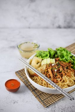 Mie ayam, tavuk ve sebzeli erişte, Endonezya geleneksel yemeği ve gri doku arka planı..