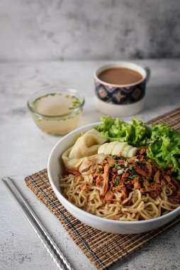 Mie ayam, tavuk ve sebzeli erişte, Endonezya geleneksel yemeği ve gri doku arka planı..