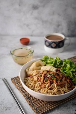 Mie ayam, tavuk ve sebzeli erişte, Endonezya geleneksel yemeği ve gri doku arka planı..