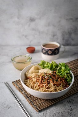 Mie ayam, tavuk ve sebzeli erişte, Endonezya geleneksel yemeği ve gri doku arka planı..