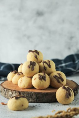 Üstü çikolatalı kek topu. Endonezya keki ya da kurabiyesi. Ahşap yer haritasında gri ve doku arka planında servis edilir. Çikolatalı N harfi.