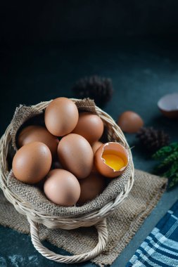 Arka plandaki sepette taze çiğ tavuk yumurtası. Bir tavuk yumurtası kırıldı.