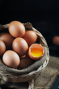 Arka plandaki sepette taze çiğ tavuk yumurtası. Bir tavuk yumurtası kırıldı.