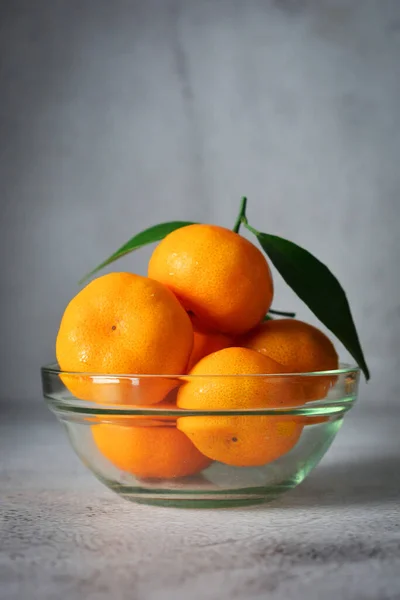 ガラスボウルに オレンジ色の果物がたくさんあります グレーとテクスチャの背景にマンダリンオレンジのフルーツ ロイヤリティフリーのストック写真