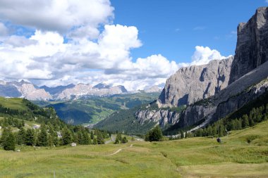 Alta Badia (Dolomiti) - Passo Sella 'nın güzel yaz dağ manzarası ve Sassopiatto ve Sassolungo, Langkofel, Dolomiti, Sella grubu. Yeşil çayırlar ve otlaklar, dağlık tepeler ve mavi gökyüzü.