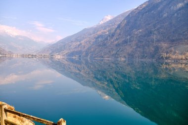 Orman gölünün panoramik manzarası. Açık mavi gökyüzü ve yağmurdan sonra parlayan dramatik bulutlar. İsviçre 'deki Poschiavo Gölü. Güneşli gökyüzü.