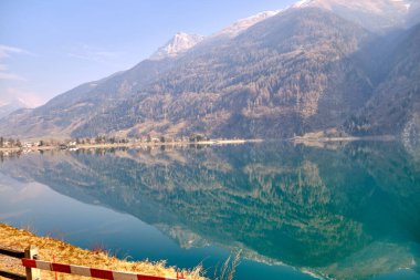 Orman gölünün panoramik manzarası. Açık mavi gökyüzü ve yağmurdan sonra parlayan dramatik bulutlar. İsviçre 'deki Poschiavo Gölü. Güneşli gökyüzü.