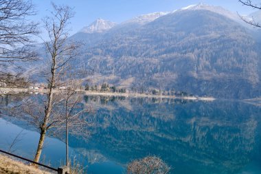 Orman gölünün panoramik manzarası. Açık mavi gökyüzü ve yağmurdan sonra parlayan dramatik bulutlar. İsviçre 'deki Poschiavo Gölü. Güneşli gökyüzü.