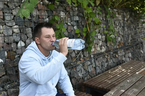 Orta yaşlı adam su içiyor.