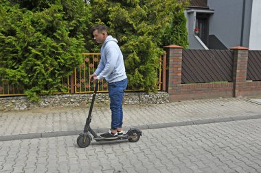 Genç adam şehirde scooter kullanıyor.