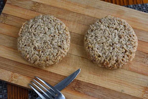 Doğrama tahtasındaki çiğ hamburgerler