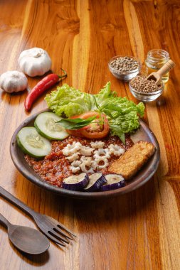 Baharatlı biber soslu kızarmış kalamar mı yoksa ahşap masadaki çömlek tabağında sambal mı?