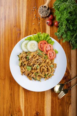 Erişteleri kızart ya da sebze, tavuk, yumurta ve eti ahşap masada beyaz tabakta karıştır.