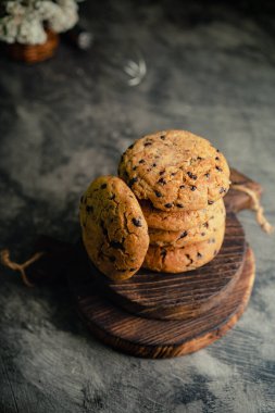 Kırsal ahşap bardak altlığı ve soyut arka planda ev yapımı çikolatalı kurabiyeler.