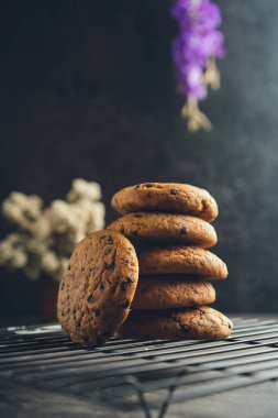 Siyah soğutma tepsisinde ev yapımı çikolatalı kurabiyeler ve soyut arka plan.