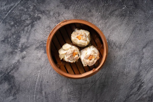 stock image Chinese steamed dumplings or  Dim Sum in bamboo steamer on dark abstract background