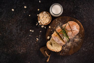 Tahta bardak altlığı ve kırsal arka planda dilimlenmiş baget ekmeği. Esnaf Ekşi Ekmek.