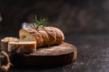 Tahta bardak altlığı ve kırsal arka planda dilimlenmiş baget ekmeği. Esnaf Ekşi Ekmek.