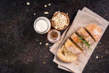 Tahta bardak altlığı ve kırsal arka planda dilimlenmiş baget ekmeği. Esnaf Ekşi Ekmek.