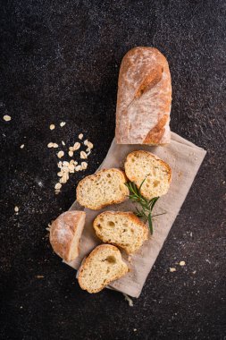 Tahta bardak altlığı ve kırsal arka planda dilimlenmiş baget ekmeği. Esnaf Ekşi Ekmek.