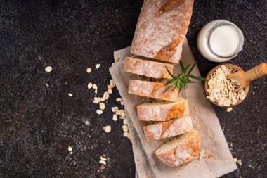 Tahta bardak altlığı ve kırsal arka planda dilimlenmiş baget ekmeği. Esnaf Ekşi Ekmek.