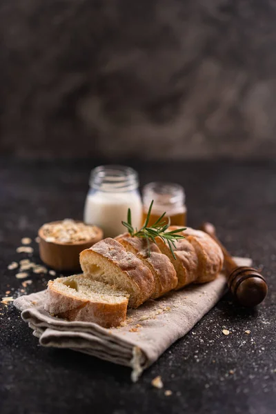 stock image Sliced baguette bread on wooden coaster and rustic background. Artisan Sourdough bread.