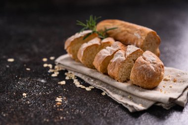 Tahta bardak altlığı ve kırsal arka planda dilimlenmiş baget ekmeği. Esnaf Ekşi Ekmek.