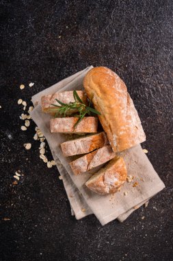 Tahta bardak altlığı ve kırsal arka planda dilimlenmiş baget ekmeği. Esnaf Ekşi Ekmek.