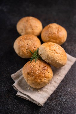 Kırsal arka planda susam tohumlu ev yapımı kahverengi çörekler. Sağlıklı zanaatkar ekmeği.