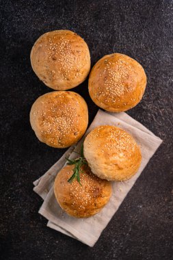 Kırsal arka planda susam tohumlu ev yapımı kahverengi çörekler. Sağlıklı zanaatkar ekmeği.